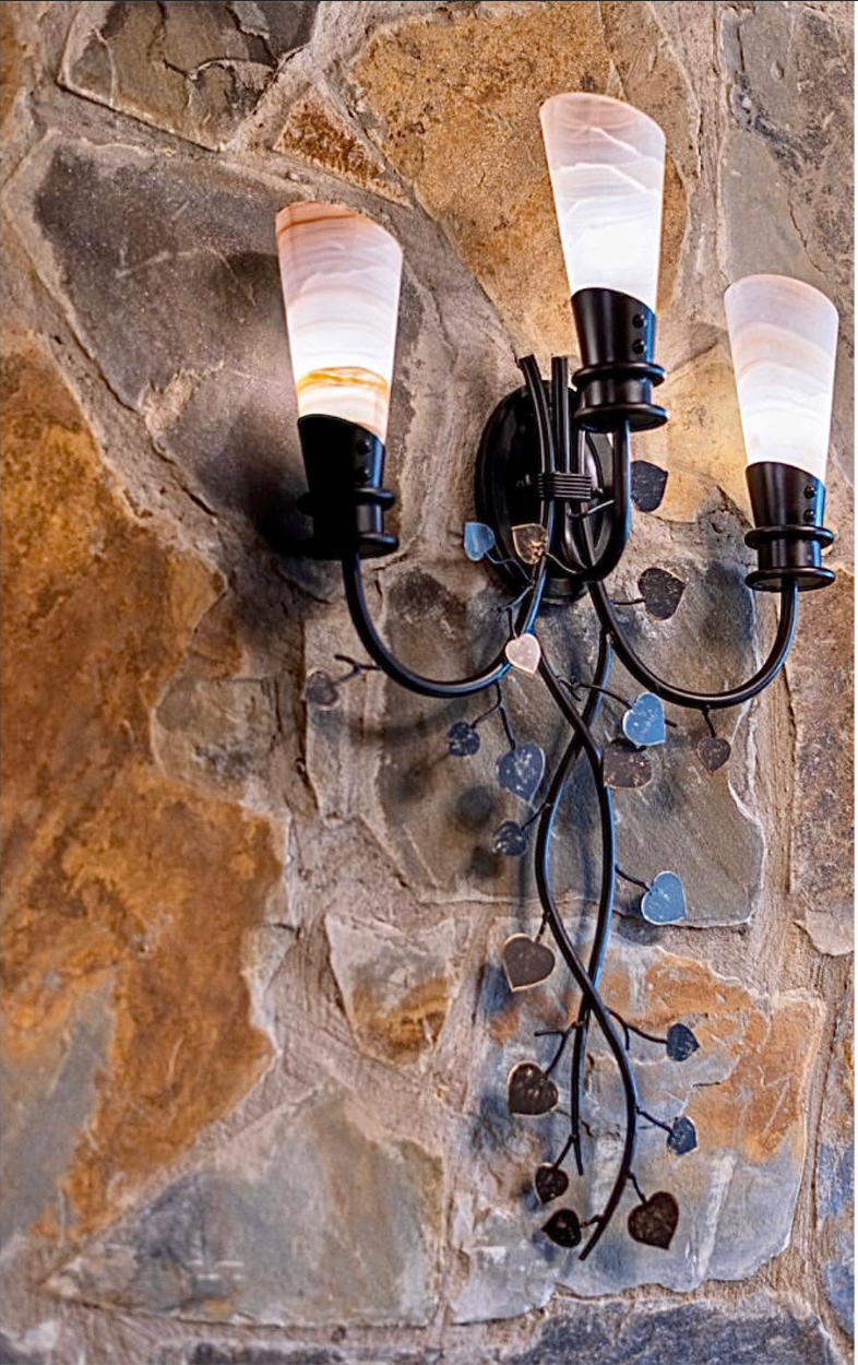 Custom iron heart-vine sconce mounted on natural stone