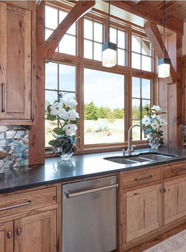 Kitchen sink framed by timber windows and pendant lights