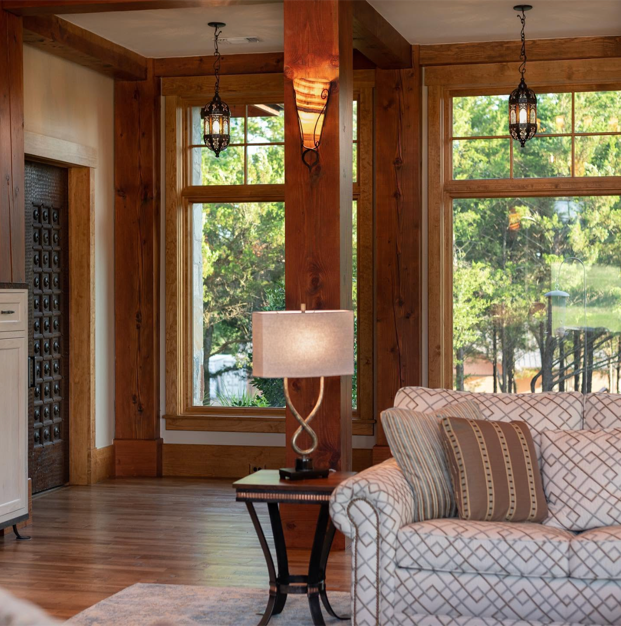 Tailored living-room seating framed by timber windows and artisan lanterns