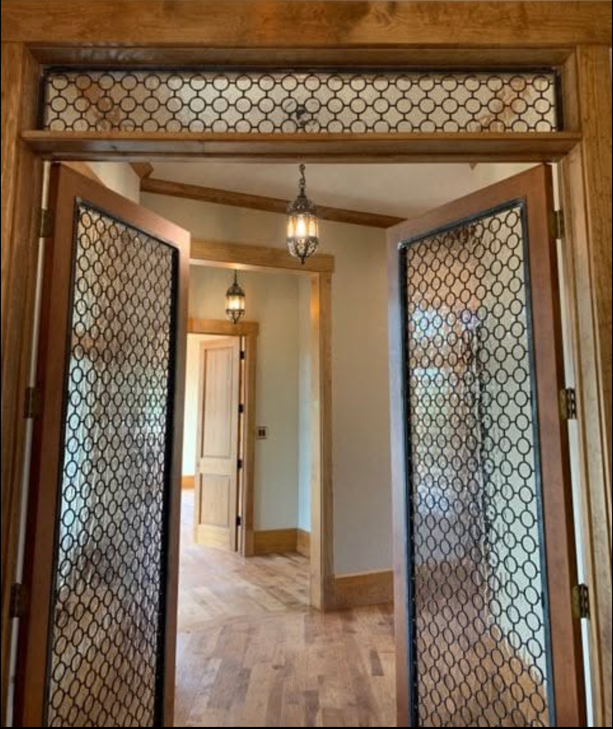 Custom metal-screen double doors with patterned transom