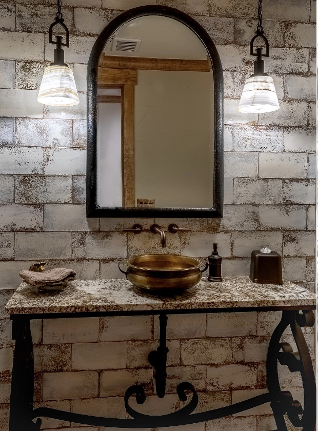 Powder room with iron console, vessel sink, and arched mirror