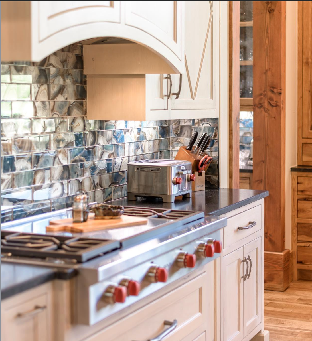 Professional range with red controls and luminous stone backsplash