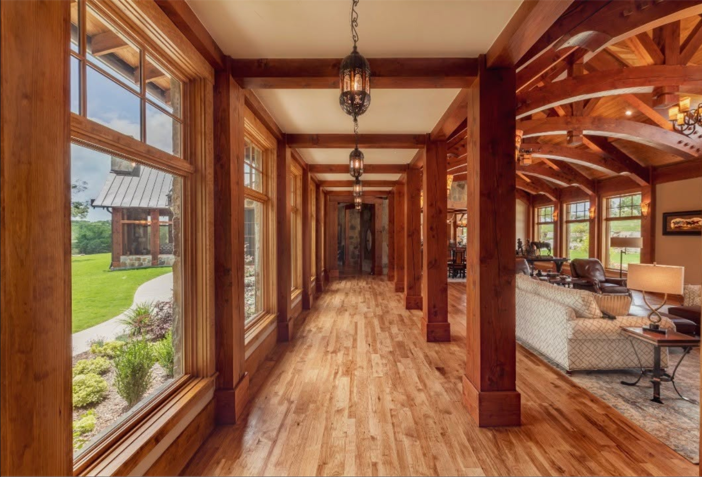 Window-lined hall opening into the timber-framed great room